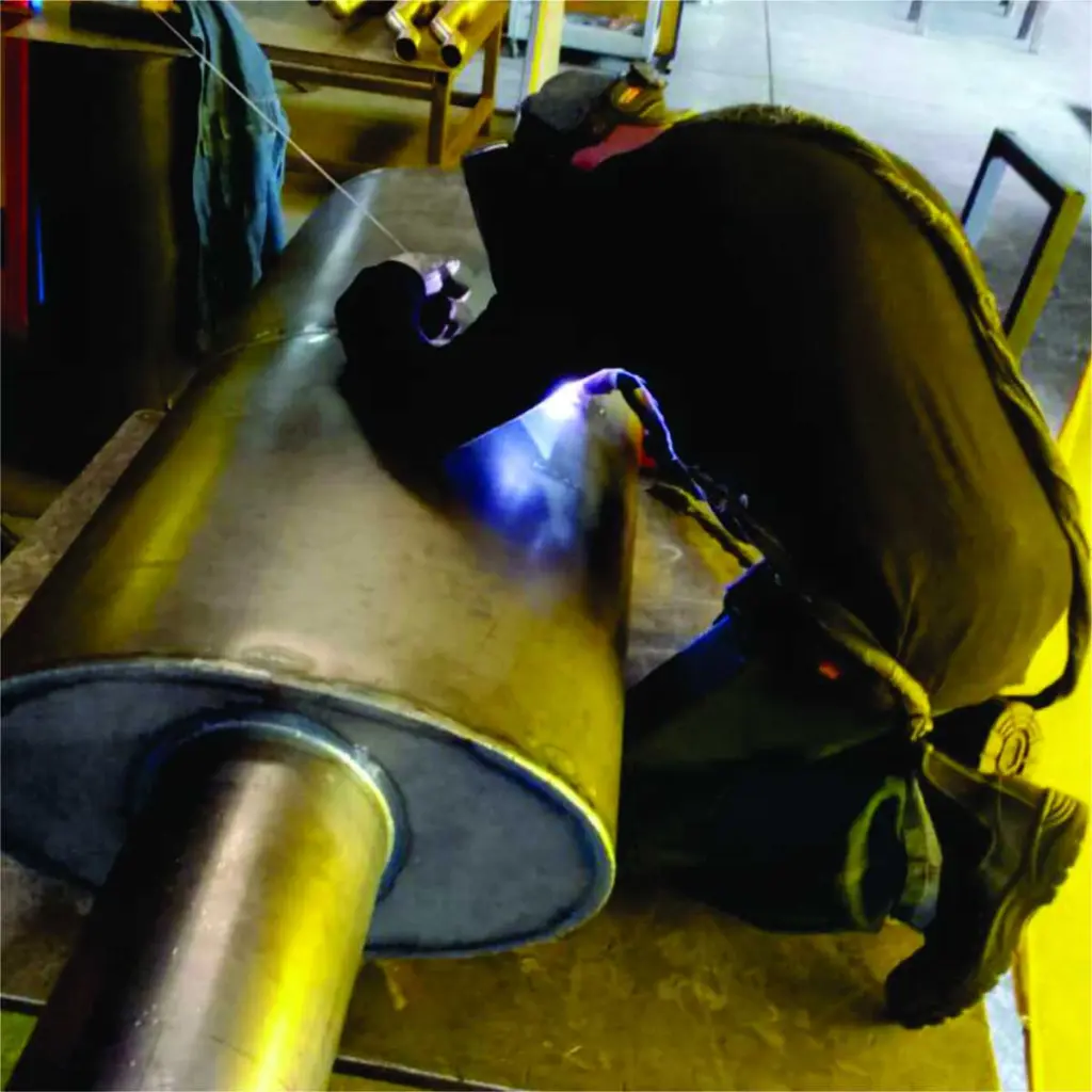 Welder fabricating a heavy-duty silencer
