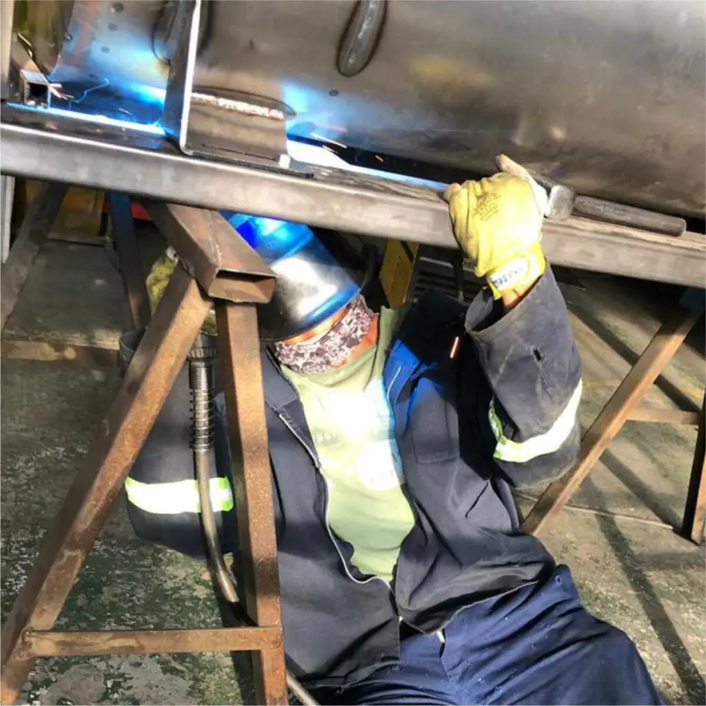 Welder working under a large exhaust body